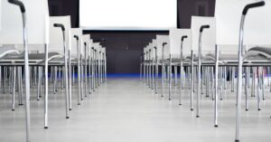 Empty modern conference room with white chairs in rows, ready for a presentation.